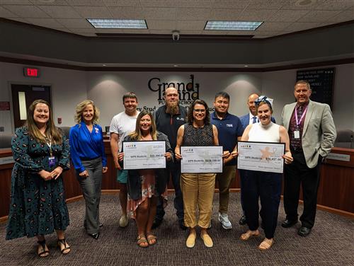 GIPS Foundation staff with the GIPS Board smiling and holding large donation checks.