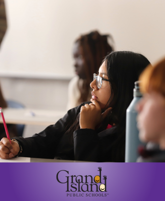  GISH Freshman Student at desk writing with a pencil while listening to teacher in class.