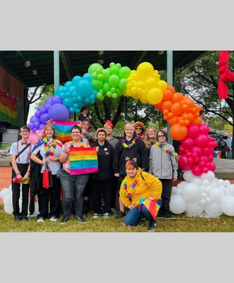  GISH LGBTSA students standing in front of a rainbow balloon display outside.