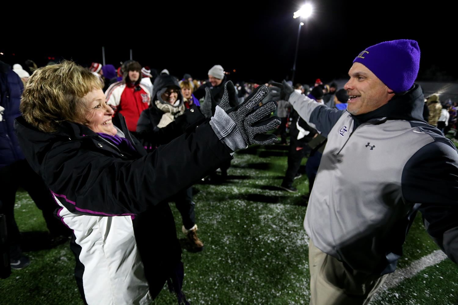 Maria & Jeff Tomlin smiling with arms open about to hug after a State Football playoff game