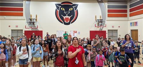 Stolley Park students and staff standing for the pledge of allegiance in their gym