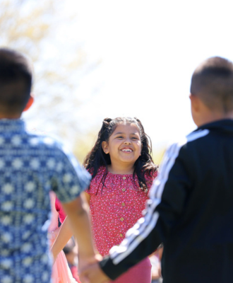  Smiling Elementary students standing in a circle outside at Howard.