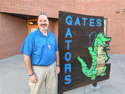 Mr. Wes Tjaden standing and smiling next to the Gates Elementary sign.