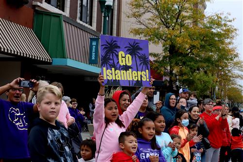 Students and community members cheering on the Islanders at a parade